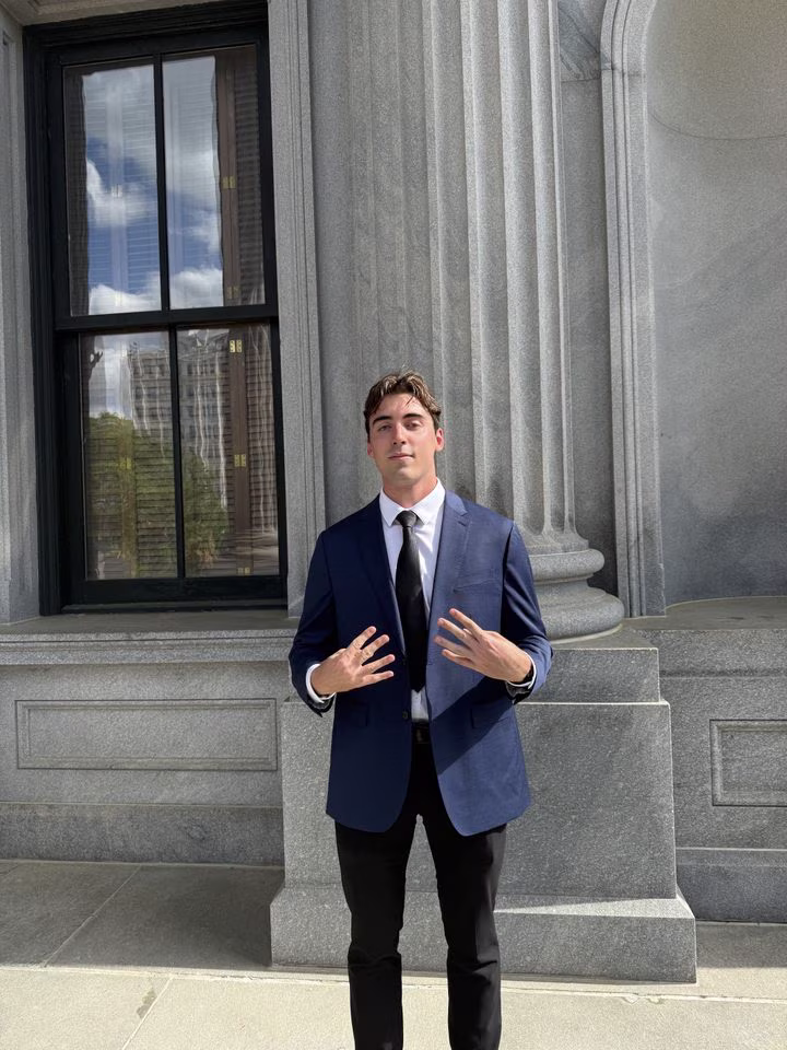 Man in dark blue suit standing in front of a stone building
